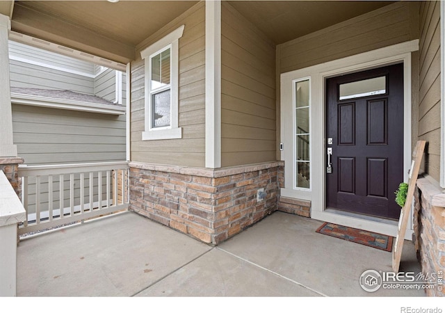 doorway to property with a porch and brick siding