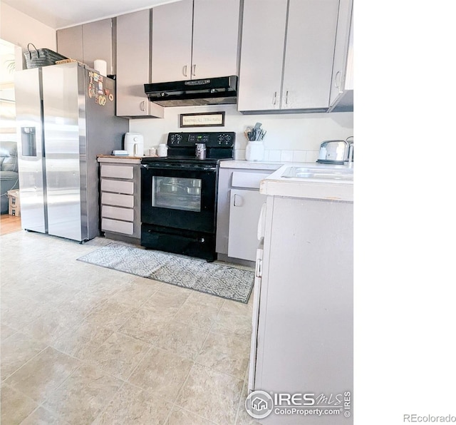 kitchen featuring stainless steel fridge, black electric range oven, gray cabinetry, and sink