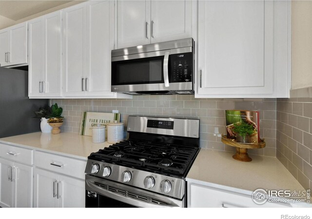 kitchen featuring stainless steel appliances, decorative backsplash, and white cabinets