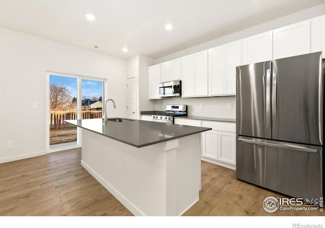 3218 Buffalo Grass Ln, Wellington, CO 80549 - kitchen with stainless steel appliances, a sink, light wood-type flooring, an island with sink, and white cabinets