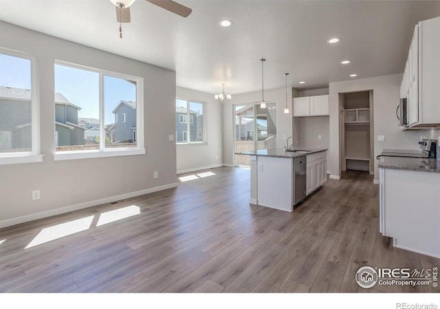 kitchen with white cabinets, sink, hanging light fixtures, appliances with stainless steel finishes, and light hardwood / wood-style floors