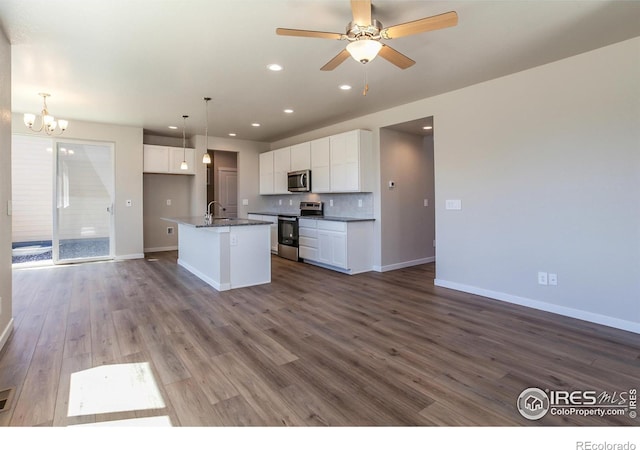 kitchen featuring white cabinets, appliances with stainless steel finishes, a center island with sink, and hanging light fixtures