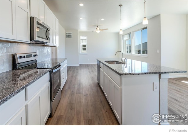 kitchen featuring white cabinets, sink, an island with sink, appliances with stainless steel finishes, and a healthy amount of sunlight