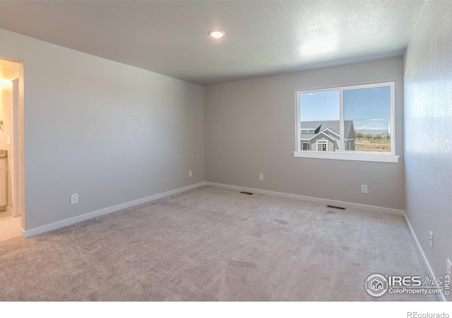 empty room with light carpet and a textured ceiling