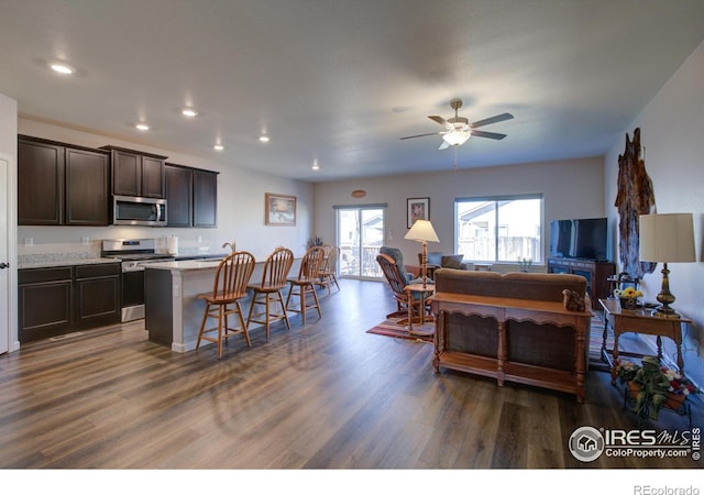 kitchen featuring dark wood-type flooring, a breakfast bar, a kitchen island, dark brown cabinets, and appliances with stainless steel finishes