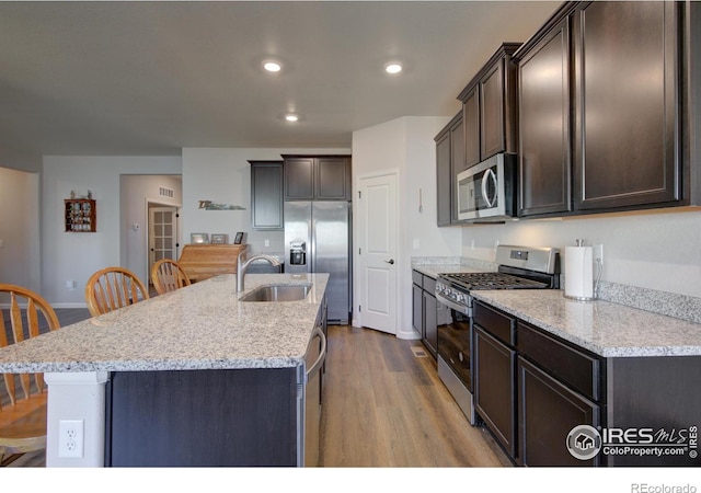 kitchen with a center island with sink, sink, light wood-type flooring, and stainless steel appliances