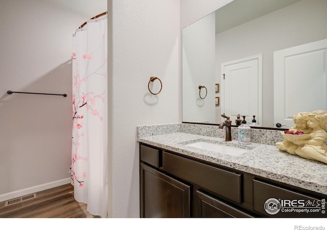 bathroom with hardwood / wood-style floors, vanity, and walk in shower