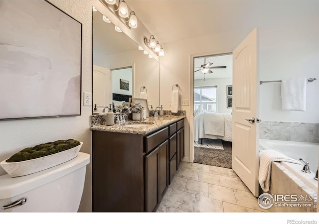 bathroom featuring vanity, a relaxing tiled tub, toilet, and ceiling fan