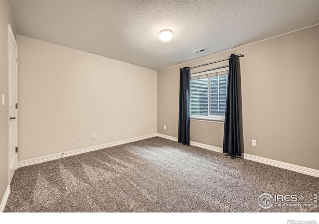 unfurnished room featuring carpet and a textured ceiling