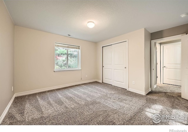 unfurnished bedroom featuring carpet flooring, a textured ceiling, and a closet