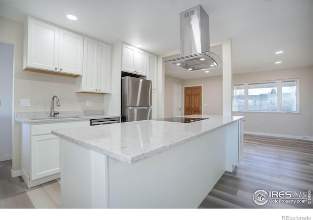 kitchen with white cabinets, sink, light wood-type flooring, island range hood, and stainless steel refrigerator