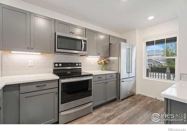 3583 Booth Falls Dr, Loveland, CO 80538 - kitchen featuring gray cabinetry, decorative backsplash, wood-type flooring, and appliances with stainless steel finishes