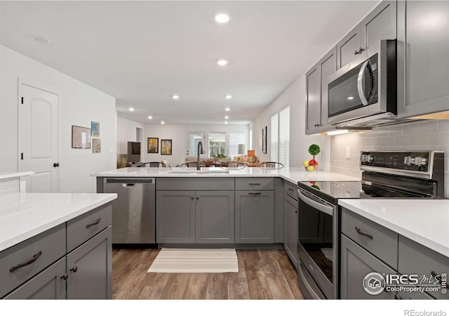 3583 Booth Falls Dr, Loveland, CO 80538 - kitchen with kitchen peninsula, gray cabinetry, stainless steel appliances, sink, and dark hardwood / wood-style floors