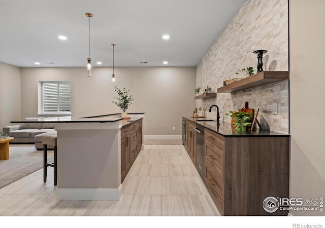 kitchen featuring pendant lighting, dishwasher, decorative backsplash, sink, and a kitchen breakfast bar