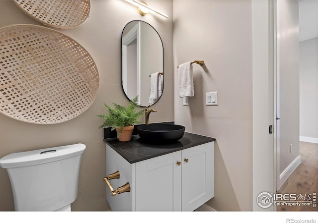 bathroom with wood-type flooring, toilet, and vanity