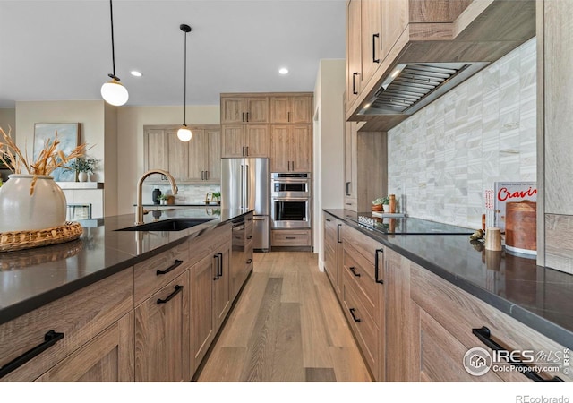 kitchen featuring tasteful backsplash, light hardwood / wood-style floors, sink, hanging light fixtures, and appliances with stainless steel finishes