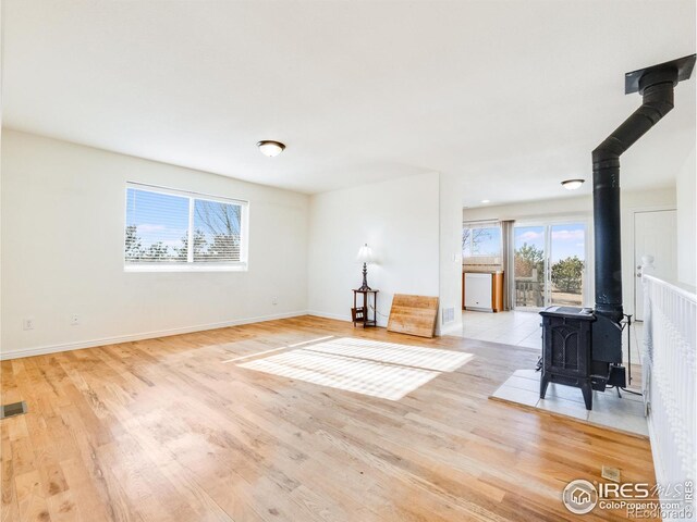 unfurnished living room featuring light wood-type flooring and a wood stove