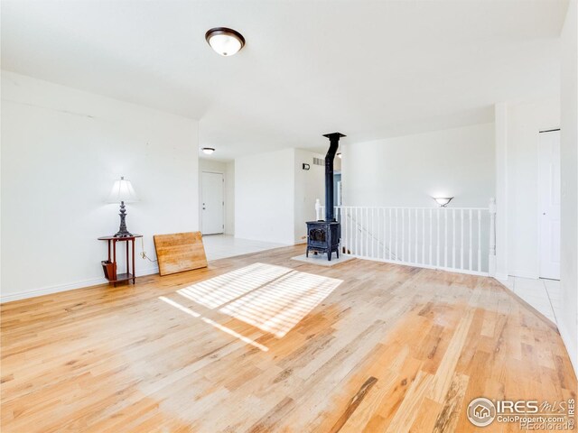 unfurnished living room featuring hardwood / wood-style flooring and a wood stove