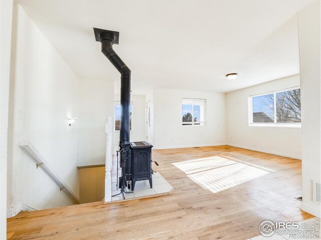 unfurnished living room featuring hardwood / wood-style floors and a wood stove