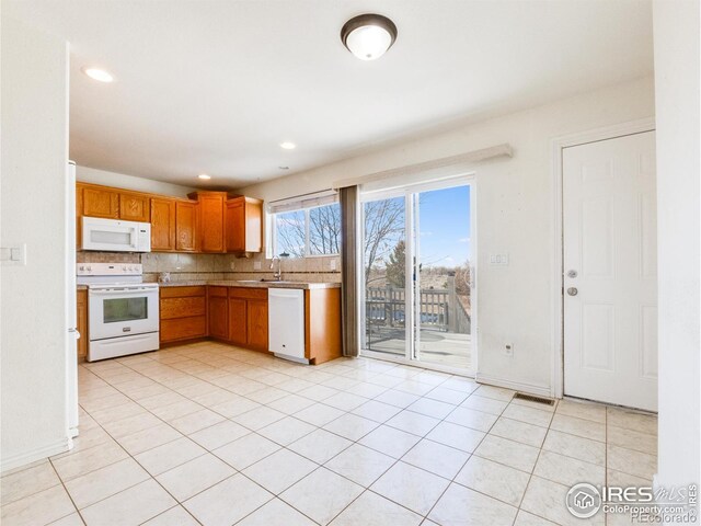 kitchen featuring decorative backsplash, sink, light tile patterned floors, and white appliances