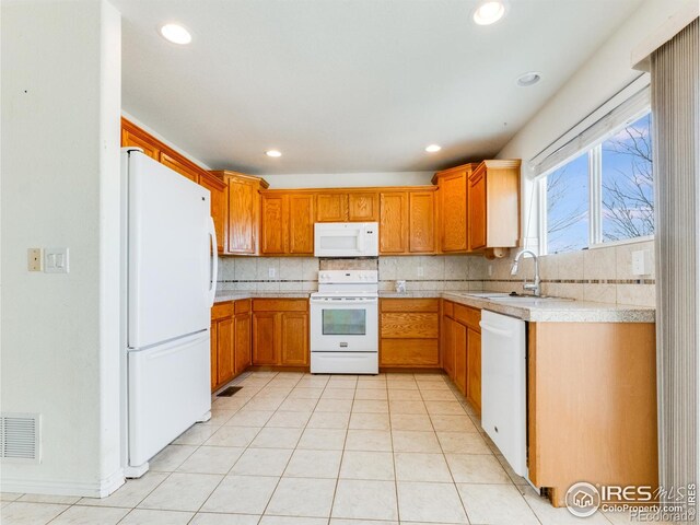 kitchen with light tile patterned flooring, white appliances, tasteful backsplash, and sink