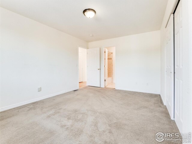 unfurnished bedroom with connected bathroom, a closet, and light colored carpet