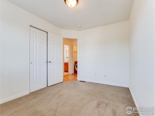 unfurnished bedroom featuring light carpet and a closet