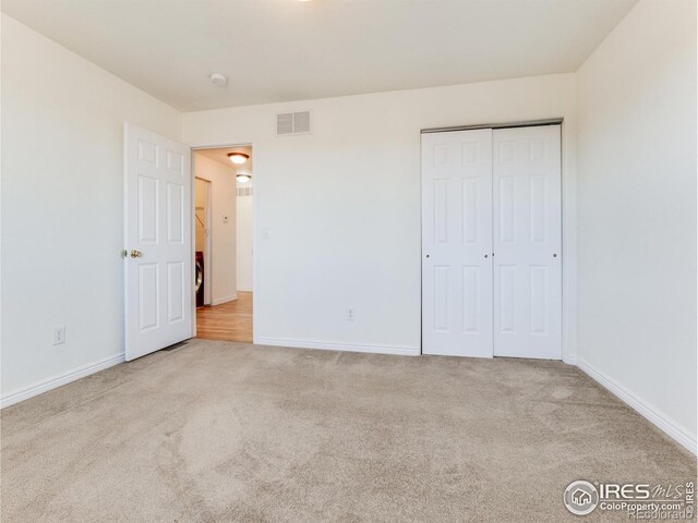 unfurnished bedroom featuring light colored carpet and a closet