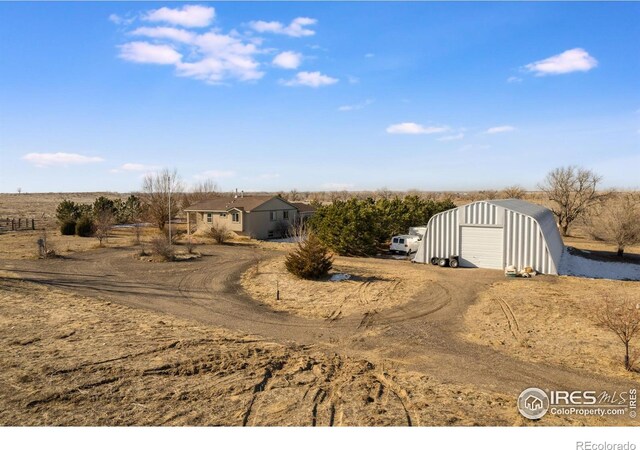 view of front facade with a rural view, a garage, and an outdoor structure