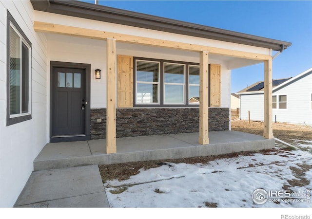 snow covered property entrance featuring a porch