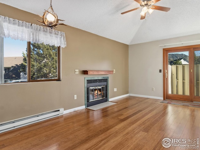 unfurnished living room with hardwood / wood-style floors, vaulted ceiling, a textured ceiling, a baseboard radiator, and a tiled fireplace