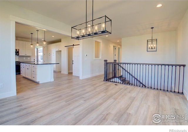 kitchen with pendant lighting, a center island, a barn door, light hardwood / wood-style floors, and white cabinetry