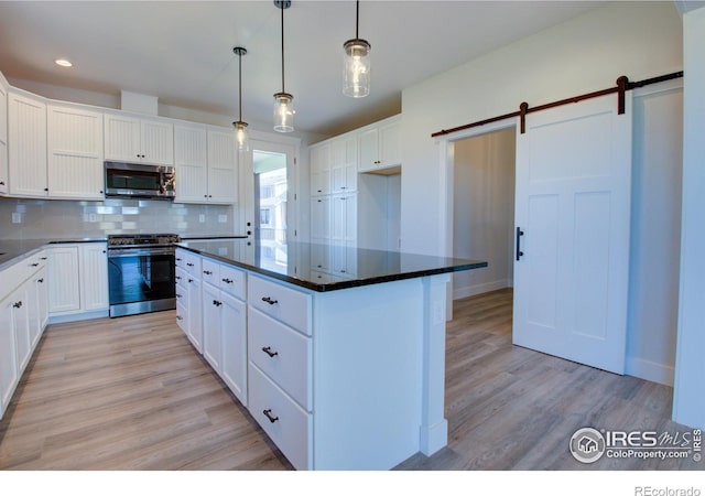 kitchen with light hardwood / wood-style flooring, a barn door, decorative light fixtures, white cabinetry, and stainless steel appliances