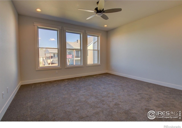 unfurnished room with dark colored carpet and ceiling fan