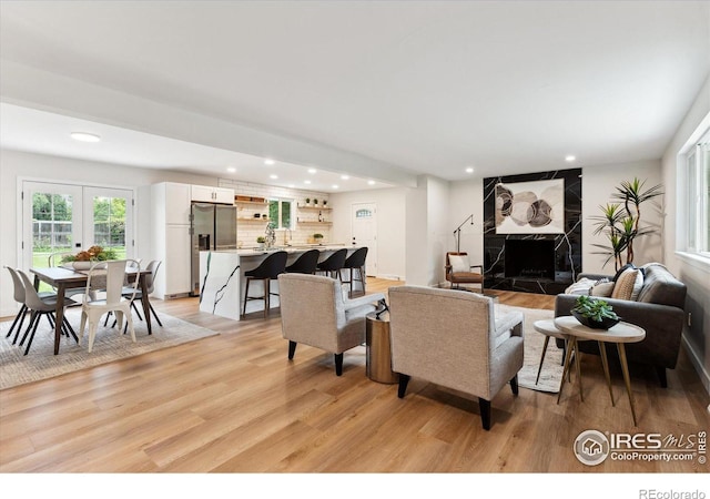 living room with a fireplace, light hardwood / wood-style flooring, and french doors