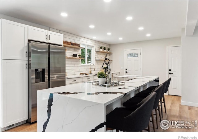 kitchen with light stone countertops, white cabinetry, a center island, light hardwood / wood-style flooring, and appliances with stainless steel finishes