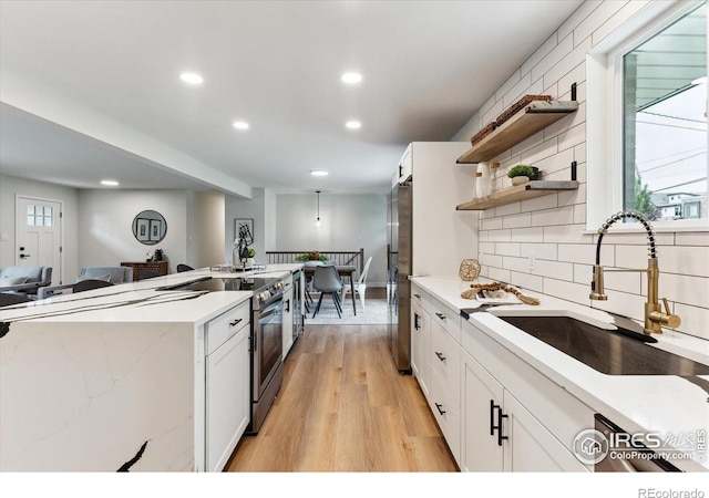 kitchen featuring white cabinetry, sink, light hardwood / wood-style floors, and appliances with stainless steel finishes