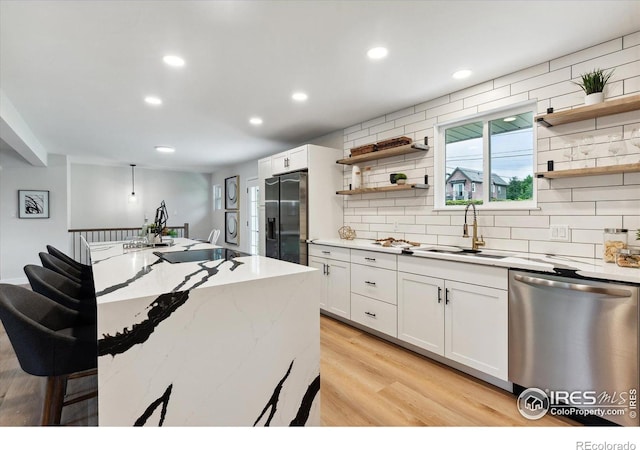 kitchen featuring sink, white cabinets, stainless steel appliances, and light hardwood / wood-style flooring