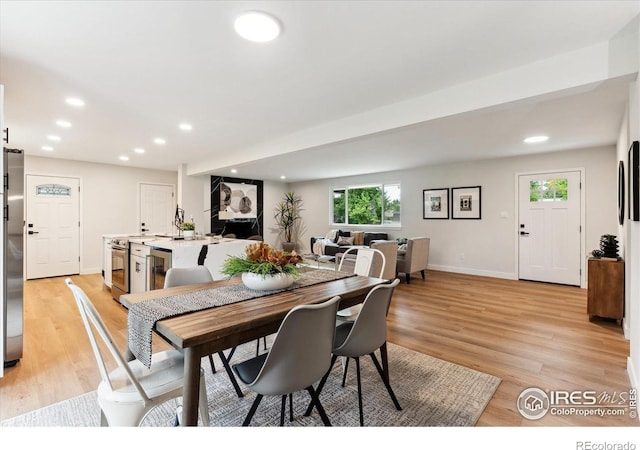 dining space with wine cooler and light hardwood / wood-style flooring