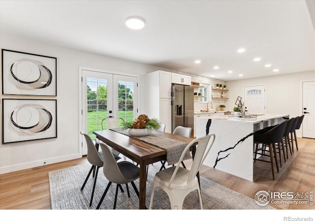 dining area with french doors, light hardwood / wood-style floors, and sink