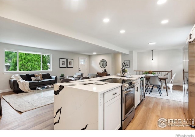 kitchen featuring appliances with stainless steel finishes, light hardwood / wood-style flooring, white cabinetry, and a center island with sink