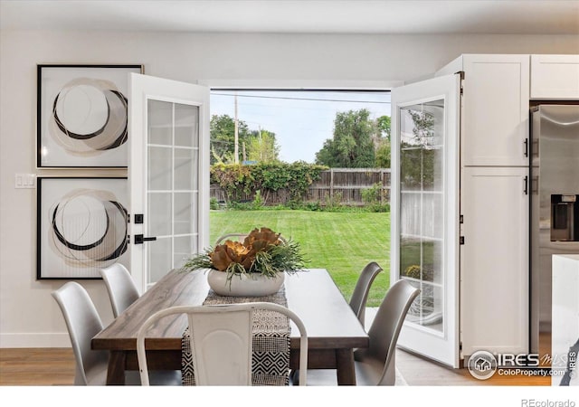 dining area featuring a healthy amount of sunlight, light hardwood / wood-style floors, and french doors