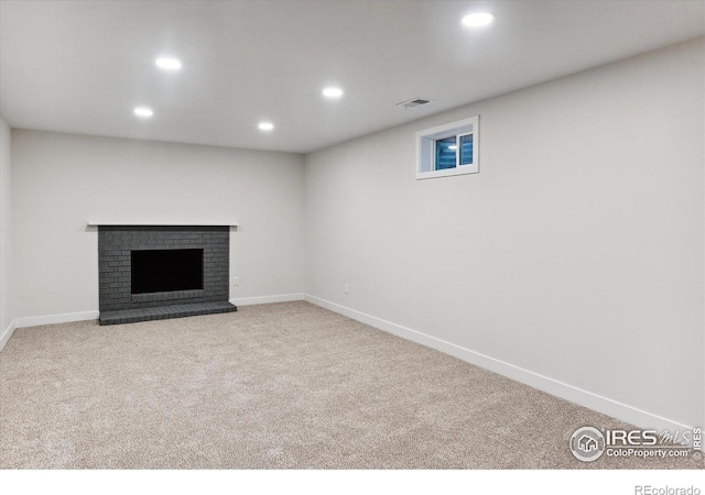 basement with light colored carpet and a brick fireplace