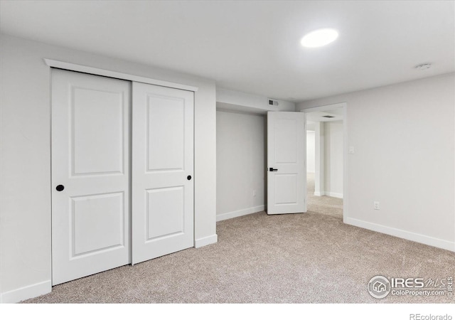 unfurnished bedroom with light carpet and a closet