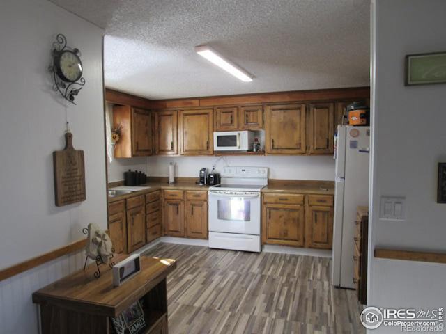 kitchen with white appliances, a textured ceiling, and light hardwood / wood-style flooring