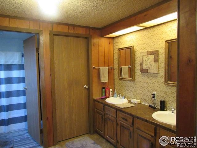 bathroom featuring vanity, a textured ceiling, and wooden walls