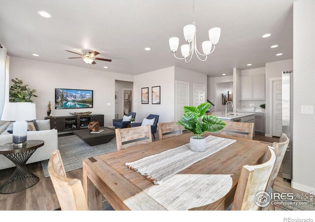 dining room with ceiling fan with notable chandelier, light hardwood / wood-style flooring, and sink