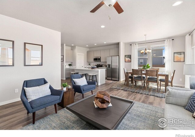 living room featuring a healthy amount of sunlight, wood-type flooring, and ceiling fan with notable chandelier