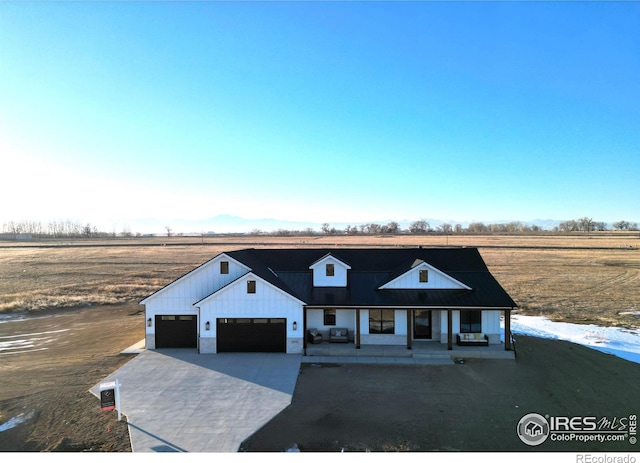 modern inspired farmhouse with a garage, a rural view, and a porch