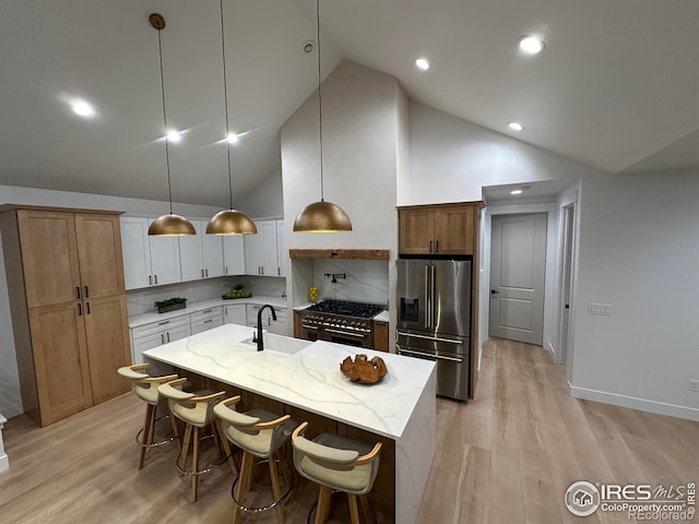 kitchen with tasteful backsplash, pendant lighting, premium appliances, an island with sink, and white cabinets